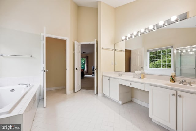 full bathroom with a high ceiling, a bath, double vanity, baseboards, and tile patterned flooring