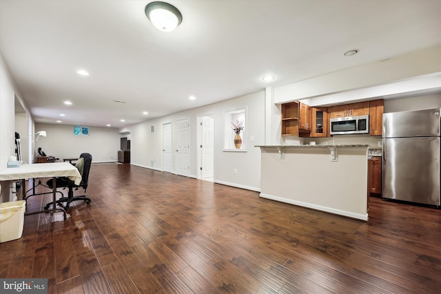 kitchen with stainless steel appliances, brown cabinets, a kitchen bar, a peninsula, and recessed lighting