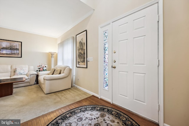 foyer with wood finished floors, ornamental molding, and baseboards