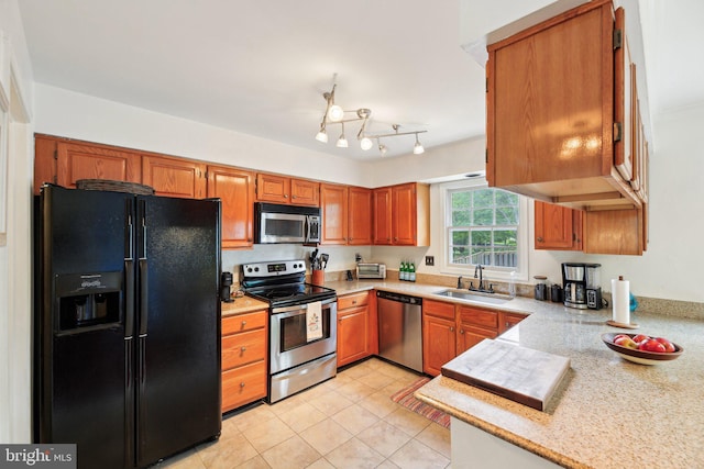 kitchen featuring stainless steel appliances, a sink, brown cabinetry, light tile patterned floors, and light stone countertops