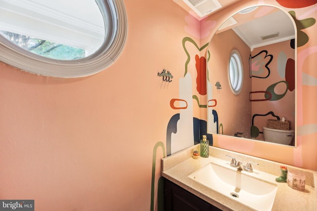 half bathroom featuring crown molding, vanity, and healthy amount of natural light
