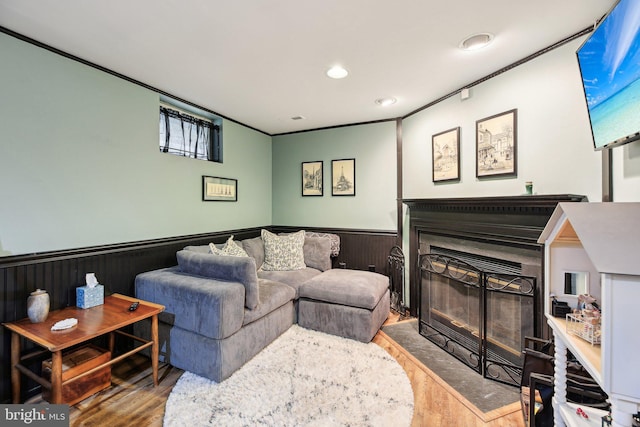 living room featuring wood finished floors, a wainscoted wall, a fireplace with flush hearth, and recessed lighting