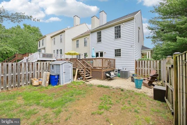 back of house with a storage shed, a deck, an outbuilding, central air condition unit, and a fenced backyard
