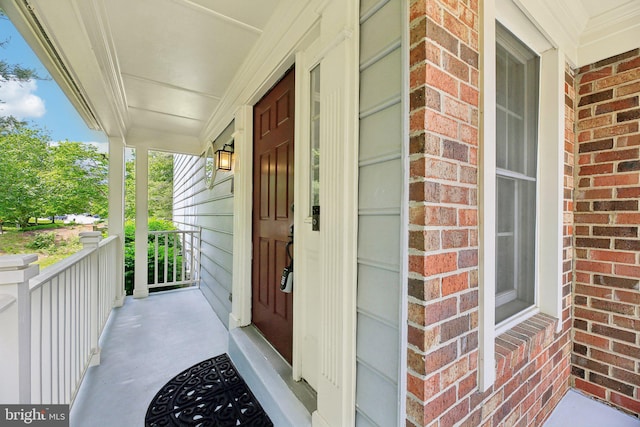entrance to property with a porch and brick siding