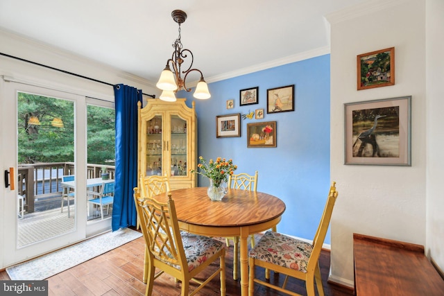 dining room with wood finished floors, ornamental molding, a chandelier, and baseboards