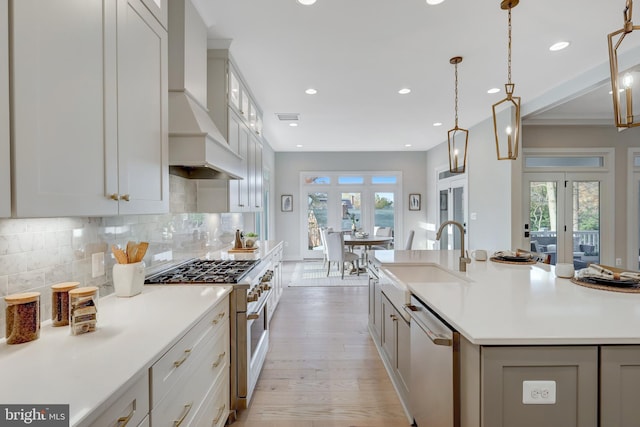 kitchen featuring high end range, dishwasher, a sink, custom range hood, and french doors
