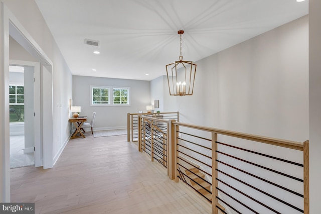 corridor with an upstairs landing, light wood-style flooring, a chandelier, recessed lighting, and baseboards
