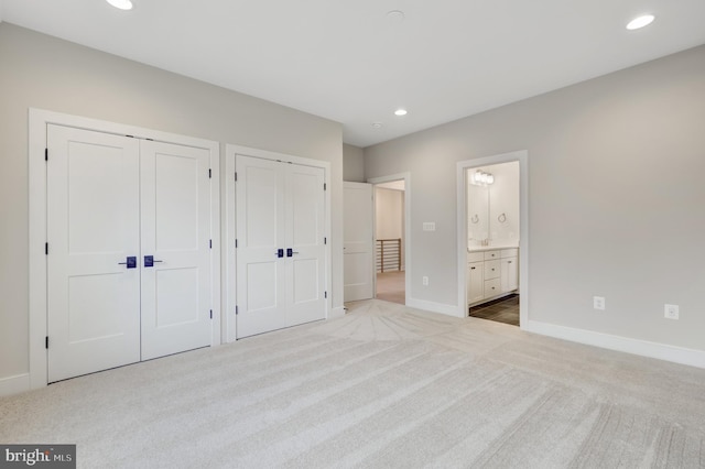 unfurnished bedroom featuring two closets, carpet floors, baseboards, recessed lighting, and connected bathroom
