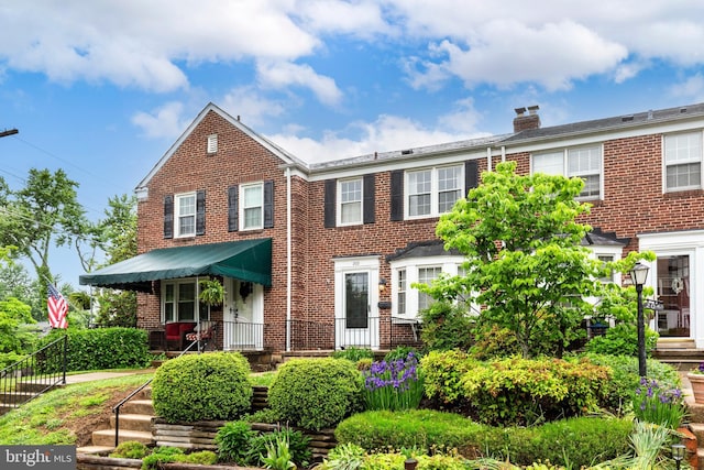 view of front of home featuring brick siding and a chimney