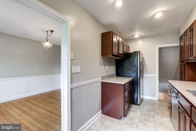 kitchen featuring light countertops, freestanding refrigerator, baseboards, and a chandelier