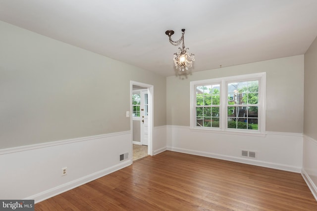 unfurnished room with wood finished floors, a chandelier, and baseboards