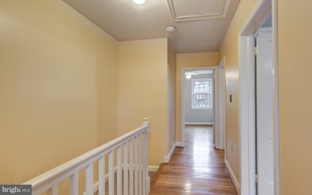 hallway featuring an upstairs landing, wood finished floors, attic access, and baseboards