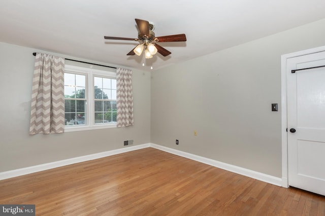 spare room featuring ceiling fan, light wood-style flooring, and baseboards
