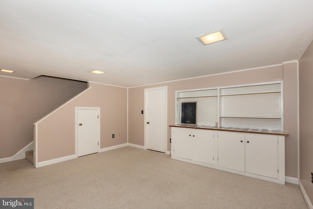 unfurnished living room featuring light carpet, baseboards, and stairs
