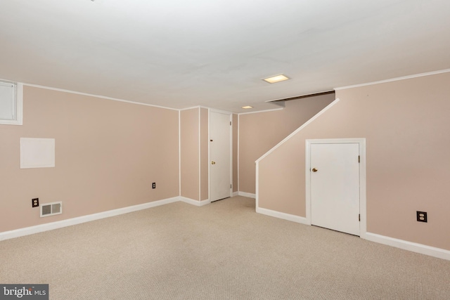 finished basement with light colored carpet, baseboards, stairs, and ornamental molding