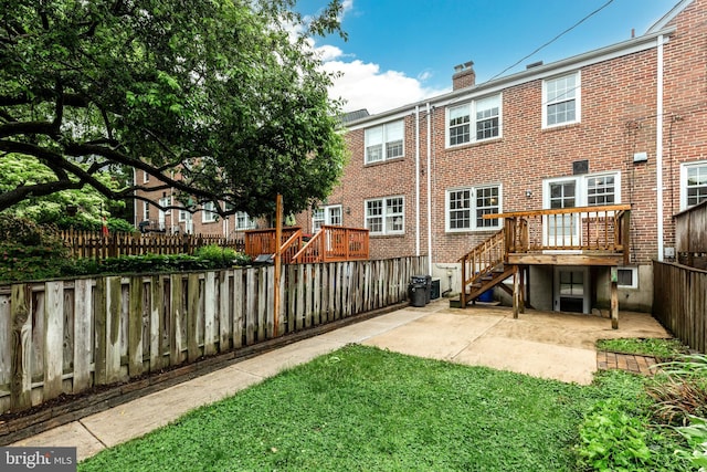 back of house featuring a fenced backyard, stairway, a patio area, brick siding, and a chimney