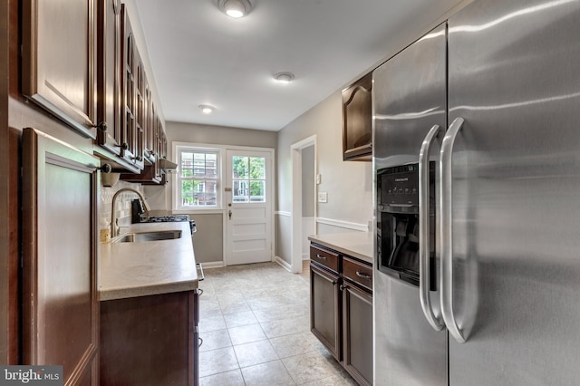 kitchen with stainless steel fridge with ice dispenser, a sink, dark brown cabinets, light countertops, and light tile patterned floors