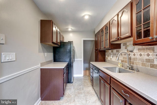 kitchen with a sink, baseboards, stainless steel appliances, backsplash, and light countertops