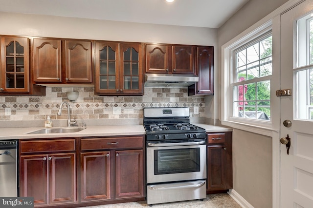 kitchen with a sink, under cabinet range hood, stainless steel appliances, light countertops, and tasteful backsplash