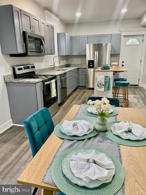 263 S Hilton St, Baltimore, MD 21229 - kitchen with appliances with stainless steel finishes, gray cabinets, a sink, and light wood-type flooring