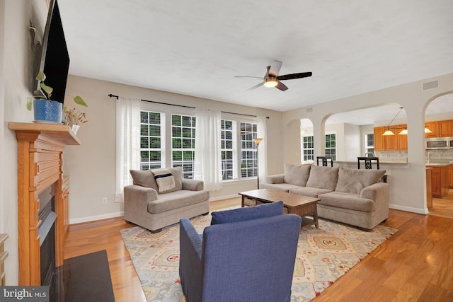 219 N Benjamin Howell St, Williamsburg, VA 23188 - living area featuring arched walkways, a fireplace with flush hearth, a ceiling fan, and light wood-type flooring