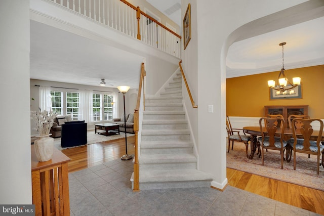 219 N Benjamin Howell St, Williamsburg, VA 23188 - staircase featuring a chandelier, tile patterned floors, a wainscoted wall, arched walkways, and ornamental molding