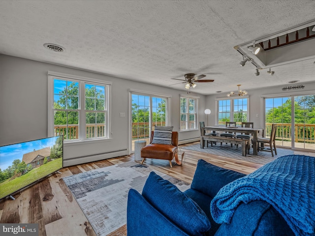 3906 Highland Ridge Rd, Berkeley Springs, WV 25411 - living area with a baseboard radiator, wood finished floors, a textured ceiling, a chandelier, and a ceiling fan