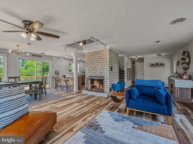 3906 Highland Ridge Rd, Berkeley Springs, WV 25411 - living room featuring wood finished floors, a textured ceiling, a brick fireplace, ceiling fan, and rail lighting