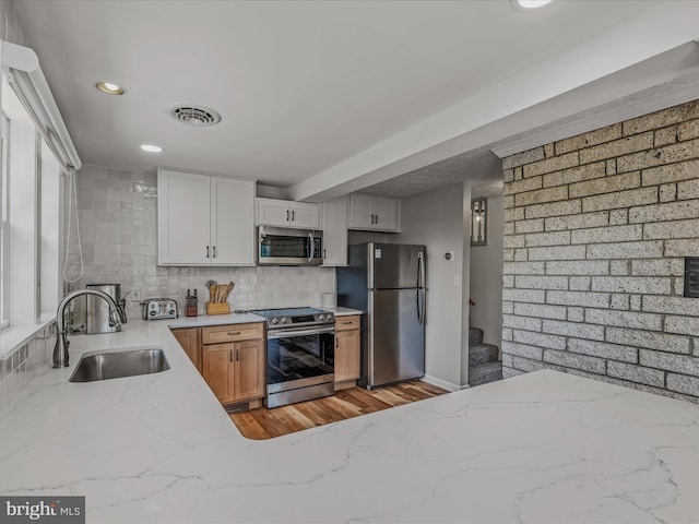3906 Highland Ridge Rd, Berkeley Springs, WV 25411 - kitchen with stainless steel appliances, a sink, light stone countertops, light wood-style floors, and backsplash