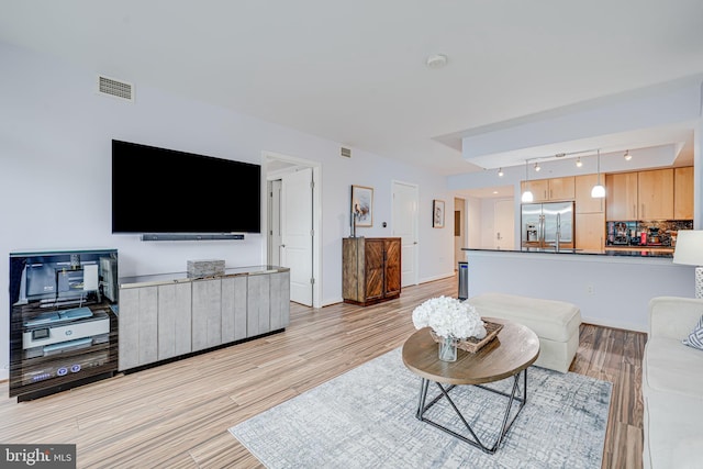 living room with rail lighting, light wood-type flooring, and baseboards