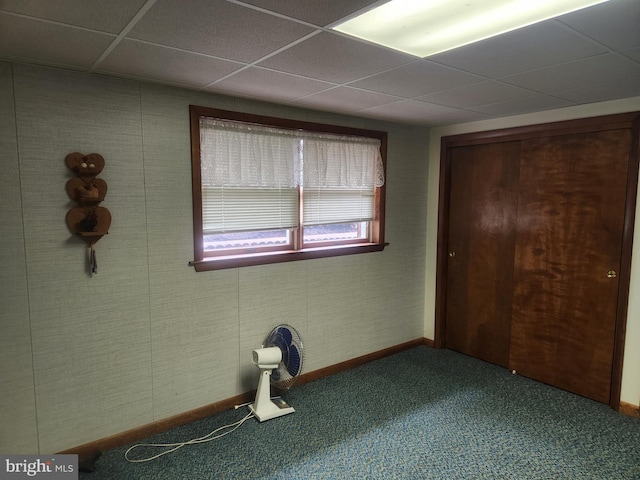 unfurnished bedroom featuring carpet floors, a paneled ceiling, and baseboards