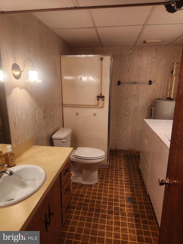 full bath with wood walls, washing machine and clothes dryer, a drop ceiling, vanity, and toilet