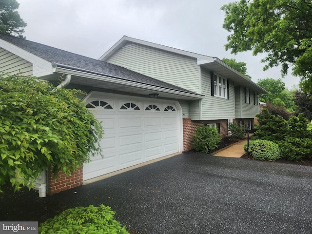 view of side of property featuring an attached garage, driveway, and brick siding