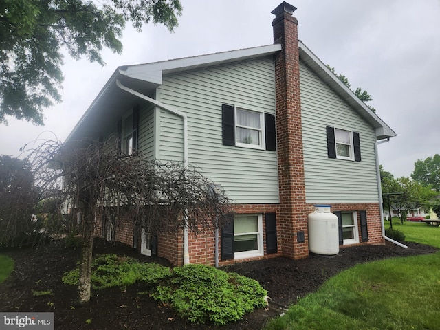 view of property exterior with a chimney and brick siding