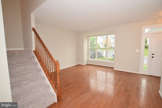 entryway with wood finished floors, baseboards, and stairs