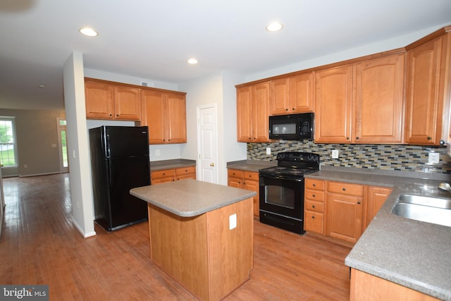 kitchen with black appliances, a center island, tasteful backsplash, light wood finished floors, and recessed lighting
