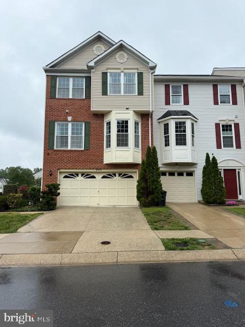 view of front facade with a garage, driveway, and brick siding