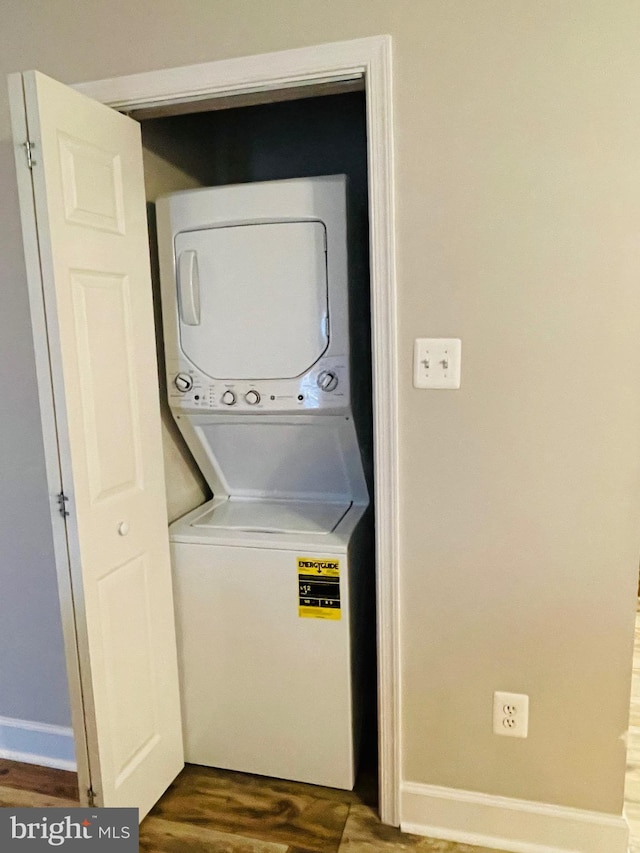 laundry area with stacked washer / drying machine and dark wood-type flooring