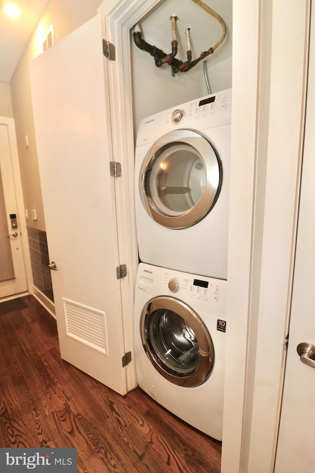 laundry area with estacked washer and dryer and dark wood-style flooring