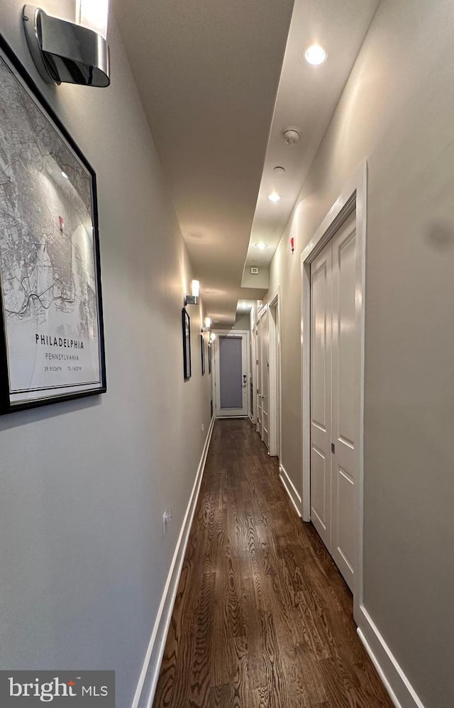 hall with dark wood finished floors, baseboards, and recessed lighting