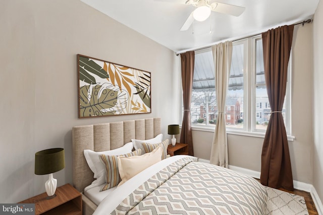 bedroom featuring baseboards, wood finished floors, and ceiling fan