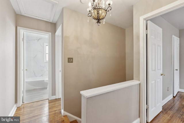 hallway with wood finished floors, baseboards, and an upstairs landing