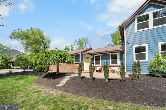 view of front facade with metal roof and a front yard