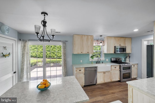 kitchen with light brown cabinets, appliances with stainless steel finishes, a sink, and light countertops