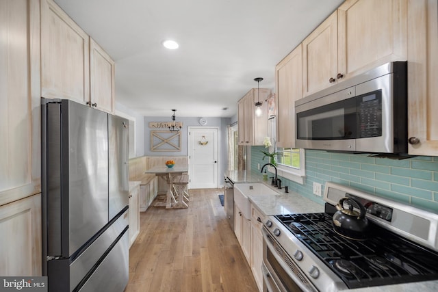 kitchen featuring appliances with stainless steel finishes, a sink, light brown cabinets, light wood-type flooring, and recessed lighting