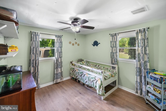 bedroom featuring multiple windows, wood finished floors, baseboards, and ceiling fan