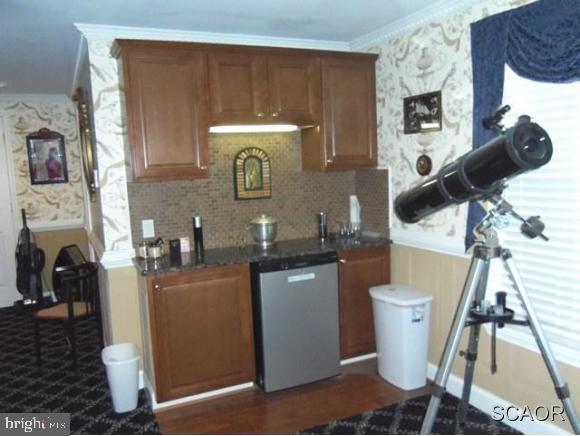 38802 Tyler Ave, Selbyville, DE 19975 - kitchen featuring dishwasher, tasteful backsplash, brown cabinetry, ornamental molding, and wallpapered walls