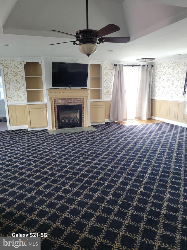 38802 Tyler Ave, Selbyville, DE 19975 - unfurnished living room featuring ceiling fan, a wainscoted wall, carpet flooring, wallpapered walls, and a brick fireplace