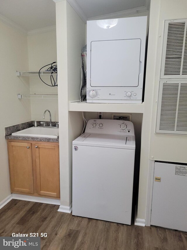 38802 Tyler Ave, Selbyville, DE 19975 - laundry room featuring a sink, ornamental molding, dark wood-type flooring, and stacked washer / dryer