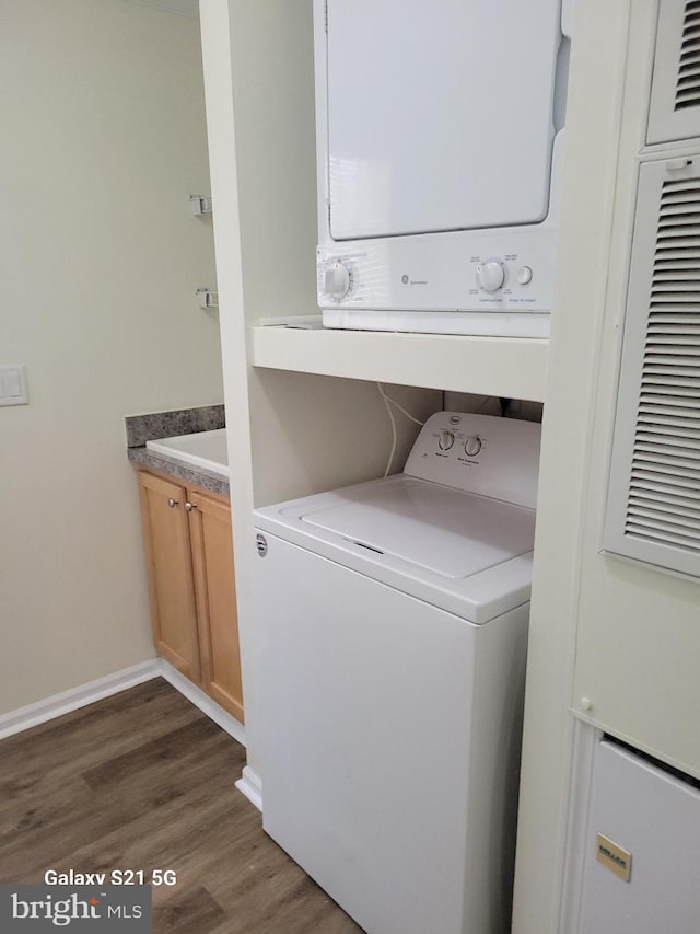 38802 Tyler Ave, Selbyville, DE 19975 - laundry area with stacked washer / drying machine, dark wood-style floors, cabinet space, and baseboards